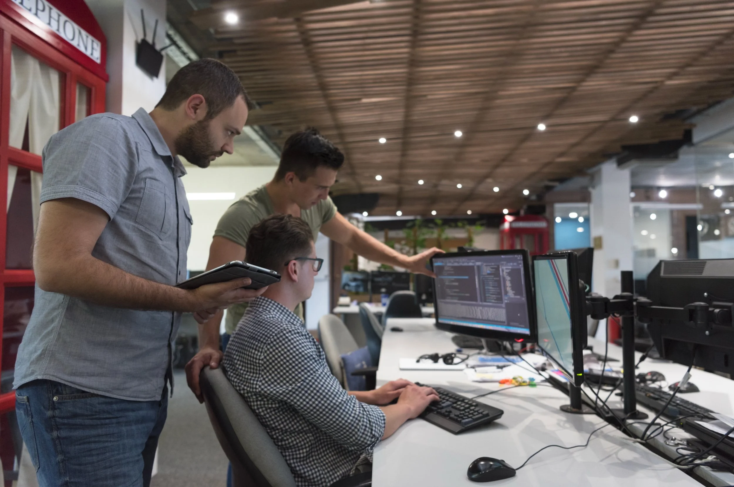three workrs at a computer console in an office setting 